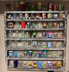 a shelf filled with lots of glasses next to a wall