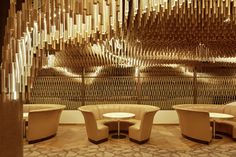 the interior of a restaurant with curved chairs and wooden partitions hanging from the ceiling