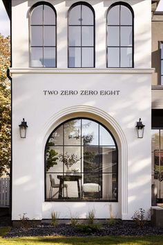 a white building with three arched windows and a table in the window sill next to it