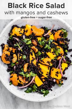 black rice salad with mangos and cashews in a white bowl on a marble table