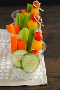 a cup filled with cucumbers, carrots and celery