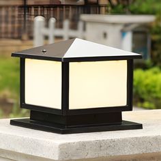 a light that is sitting on top of a cement block with grass in the background