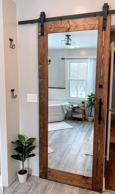 a large mirror in the middle of a room with a potted plant on the floor