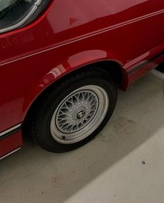 a red car parked in a garage next to a white dog laying on the ground