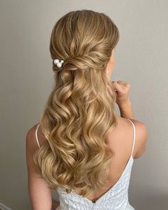 a woman with long blonde hair wearing a white dress and flower clip in her hair