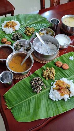 a wooden table topped with lots of food on top of a green leaf covered plate