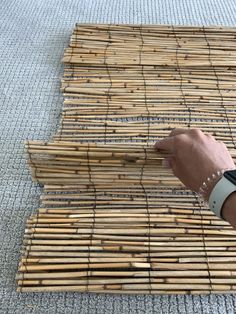 a hand is pointing at the bamboo mat on the floor that has been laid out