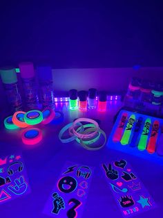 glow in the dark stickers and markers on a table with neon lights around them