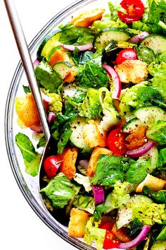 a salad in a glass bowl with a silver serving spoon on the side, ready to be eaten