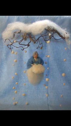 a small doll sitting on top of a cloud filled with white balls in front of a blue background