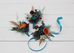 three boutonniers with flowers and leaves on them sitting on a white surface