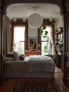 a large bed sitting under a window next to a wooden dresser in a living room