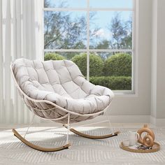 a white rocking chair sitting in front of a window