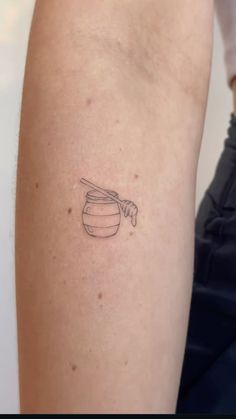 a woman with a tattoo on her arm holding a honey pot and a wooden spoon