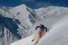 a man riding skis down the side of a snow covered slope on top of a mountain