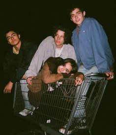 four people standing behind a shopping cart in the dark