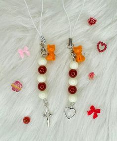 two necklaces with charms on top of a white furnishing area next to red bows and hearts