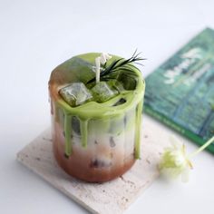 a drink in a glass with ice and sprinkles on the rim next to a book