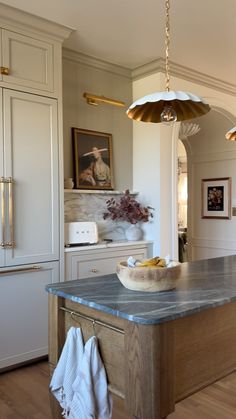 a large kitchen island with a bowl on it's countertop and two hanging lights above it