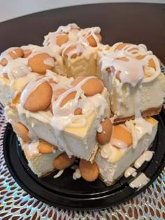 a black plate topped with pieces of cake covered in white frosting and almonds