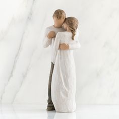 a figurine of two people hugging each other on a marble surface with a white background