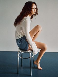 a woman sitting on top of a metal stool