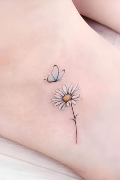 a woman's foot with two butterflies on it and a flower in the foreground