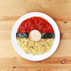 a white plate topped with spaghetti and sauce on top of a wooden table next to an instagram post