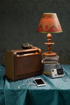 an old fashioned radio sitting on top of a table next to a lamp and cell phone