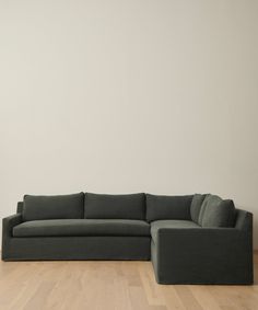 a large gray couch sitting on top of a wooden floor next to a white wall