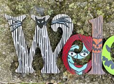 the word mom spelled out in wood letters on top of a mossy rock wall