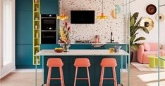 a kitchen with blue and green cabinets, pink stools, and colorful decor on the walls