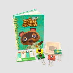 an animal crossing book, binder and keychain are sitting next to each other