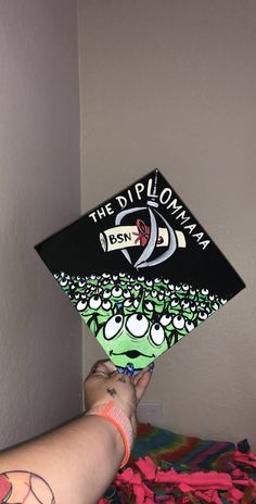 a person holding up a black and white graduation cap that says the dippoma