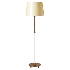 a white and gold floor lamp with a beige shade on the top, sitting on a wooden stand