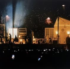 some people are standing on the side of a building with fireworks in the sky above them