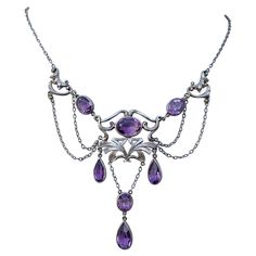 THIS IS A RARE MUSEUM QUALITY ART NOUVEAU - BELLE EPOQUE FESTOON NECKLACE WITH THE MOST GORGEOUS NATURAL OVAL AND PEAR SHAPE AMETHYST GEMS SET IN A GORGEOUS SCROLL ACANTHUS LEAF MOTIF SETTING IN AN OPEN WORK FESTOON SWAG DESIGN IN STERLING SILVER DATING TO CIRCA 1890-1900. It is very rare to find antique Art Nouveau Festoon necklaces in Sterling Silver. The combination of the gorgeous silver work with the purple amethysts is absolutely magnificent. The art nouveau scrolling acanthus leaf design Art Nouveau Gemstone Necklace For Formal Occasions, Art Nouveau Gemstone Necklaces For Formal Occasions, Formal Art Nouveau Amethyst Jewelry, Victorian Pendant Necklace, Motifs Art Nouveau, Swag Design, Festoon Necklace, Art Nouveau Necklaces, Art Nouveau Silver