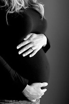 a pregnant woman holding her stomach in black and white