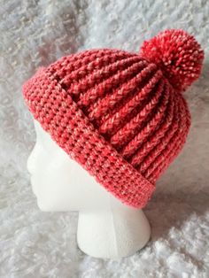 a white mannequin head wearing a red knitted hat