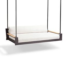 an outdoor swing bed with white cushions and wood frame, hanging from the ceiling in front of a white background