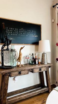 a wooden table topped with lots of bottles next to a wall mounted chalkboard on the wall