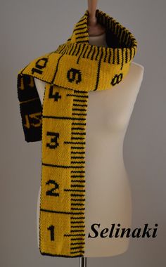 a mannequin wearing a yellow and black knitted scarf with measuring tape on it