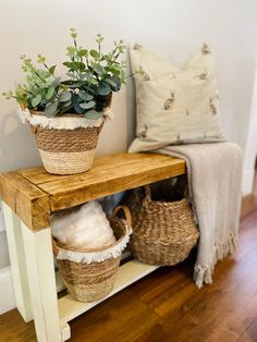 two baskets with plants sit on top of a shelf next to a pillow and throw pillows