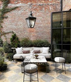 an outdoor living area with white furniture and brick walls