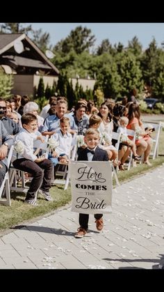 a little boy walking down the aisle holding a sign