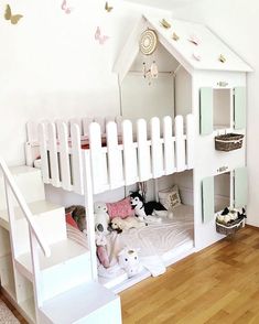 a white bunk bed with stuffed animals on the bottom and stairs leading up to it