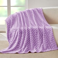 a purple blanket sitting on top of a couch next to a window