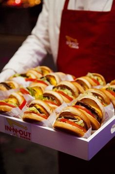 a person holding a tray full of hot dogs