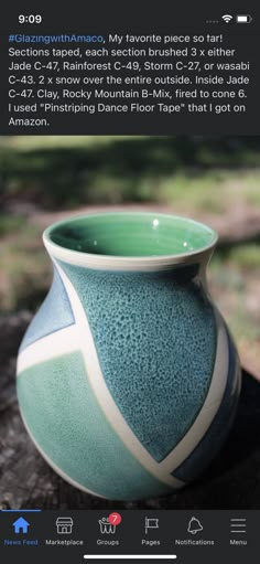 a green and white vase sitting on top of a wooden table next to a tree