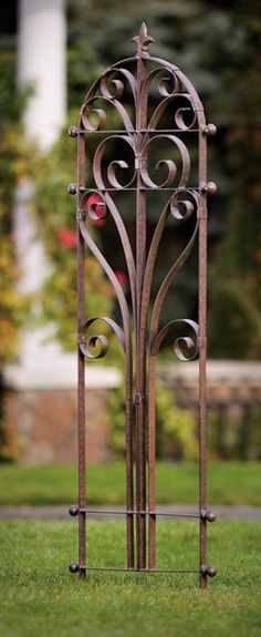 an iron gate in the middle of a grassy area